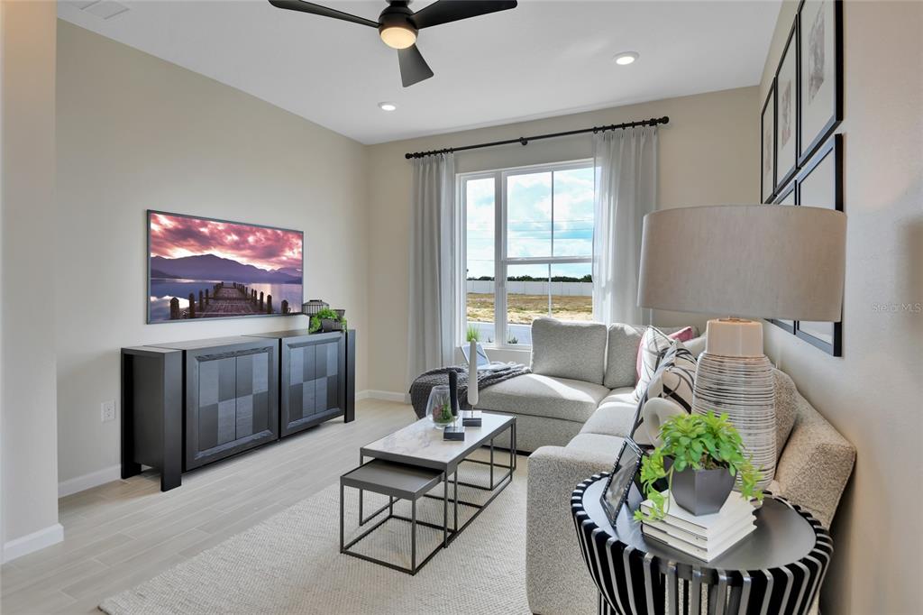 A living room features a sectional sofa, a nested coffee table, and a wall-mounted television — 164 FLAG LILLY LANE, UMATILLA, FL