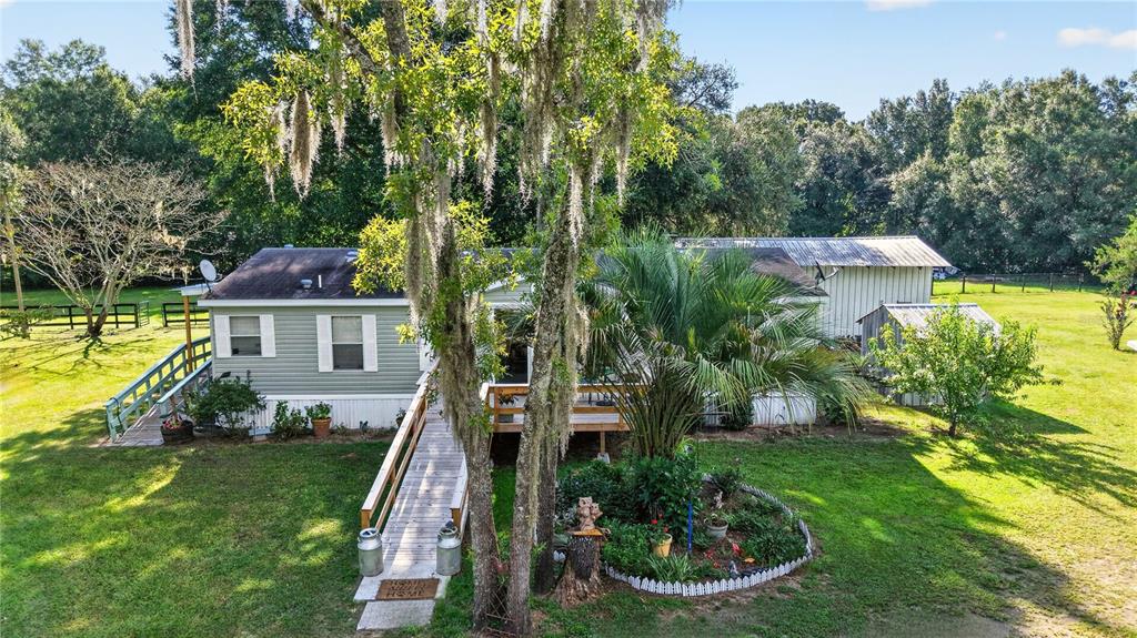 An elevated manufactured home with a wooden ramp entrance, a palm tree, and a shed — 6051 SE 148TH TERRACE, MORRISTON, FL