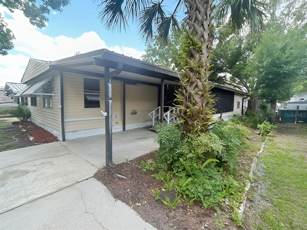 A tan mobile home features a concrete carport, a palm tree, and a screened porch — 170 PALM DRIVE, DEBARY, FL