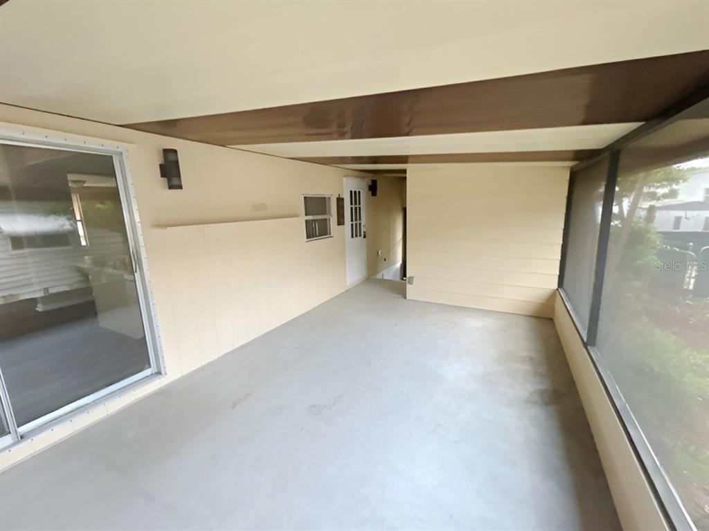 A covered patio features a concrete floor, beige walls, a sliding glass door, and screens — 170 PALM DRIVE, DEBARY, FL