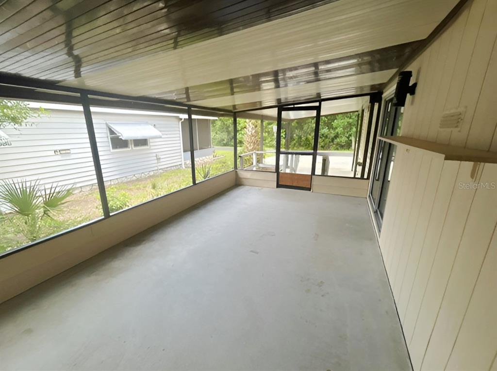 A screened-in porch features a concrete floor, paneled walls, and a metal ceiling — 170 PALM DRIVE, DEBARY, FL