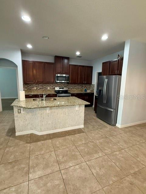A kitchen features dark wood cabinets, granite countertops, a center island, and stainless steel appliances — 3817 MT VERNON WAY, KISSIMMEE, FL
