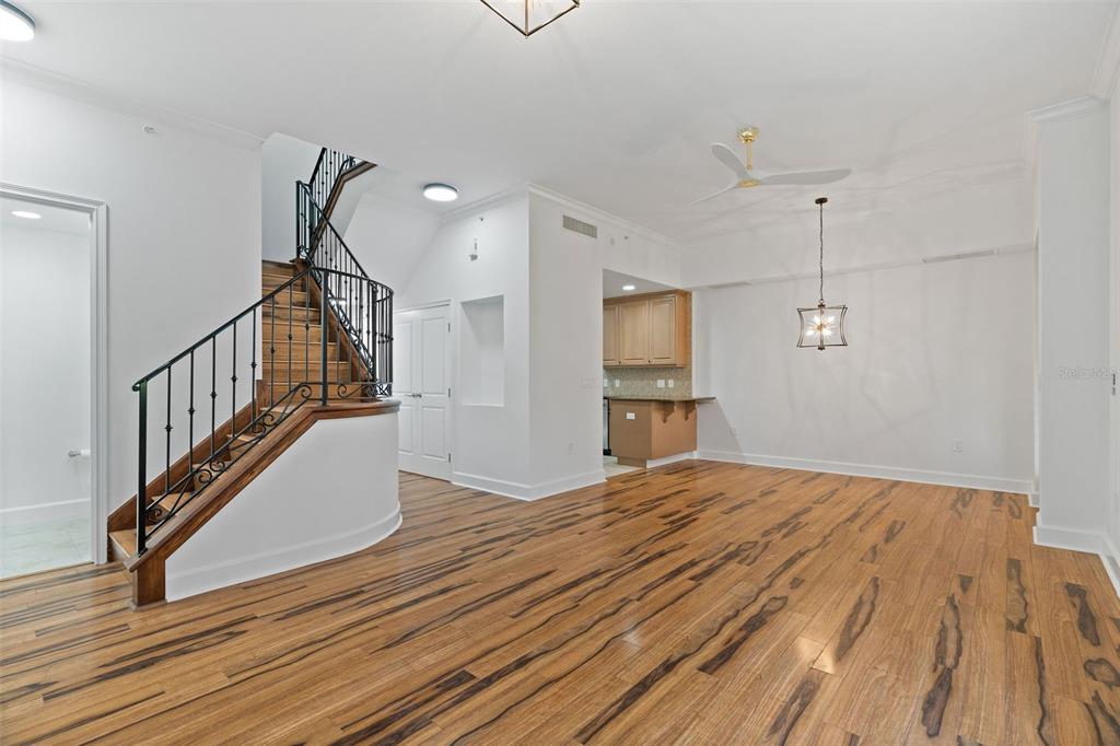 A room with hardwood floors, a curved staircase with a black railing, and a small kitchen — 300 BEACH DRIVE NE UNIT 309, ST PETERSBURG, FL