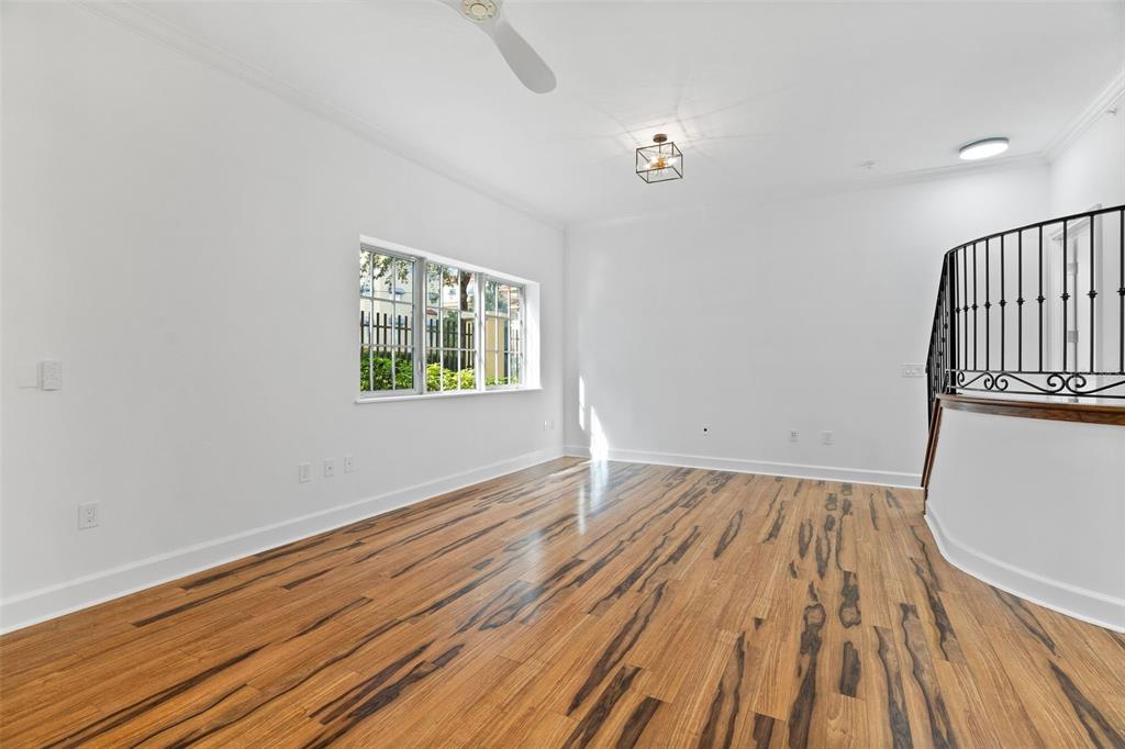 An empty room features hardwood floors, a large window, and a curved staircase with railings — 300 BEACH DRIVE NE UNIT 309, ST PETERSBURG, FL