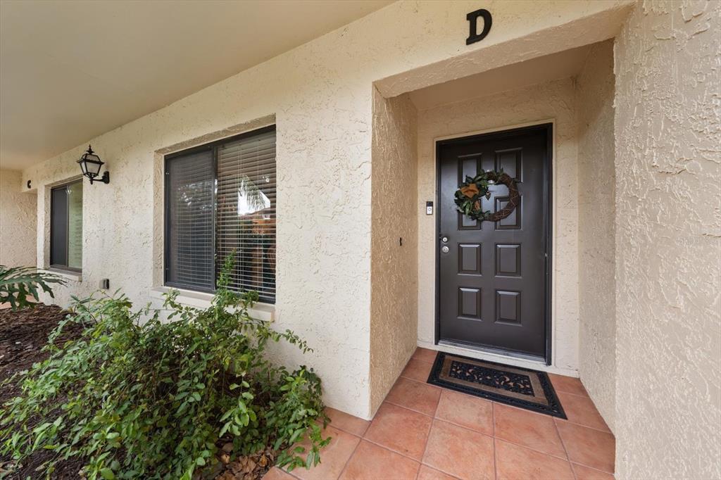 The exterior of a residential unit features a brown front door labeled with a D — 1801 E LAKE ROAD UNIT 10D, PALM HARBOR, FL