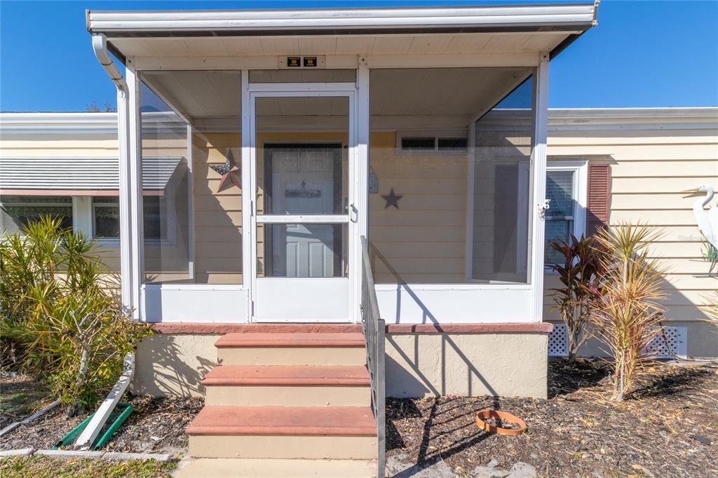 The exterior of a mobile home features a screened-in porch with steps and light siding — 153 EGRET CIRCLE, ELLENTON, FL