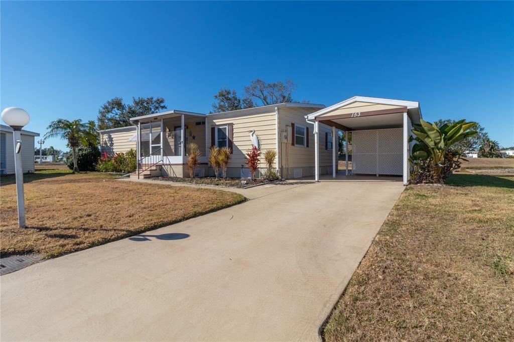A single-story manufactured home with a carport, screened porch, and concrete driveway — 153 EGRET CIRCLE, ELLENTON, FL