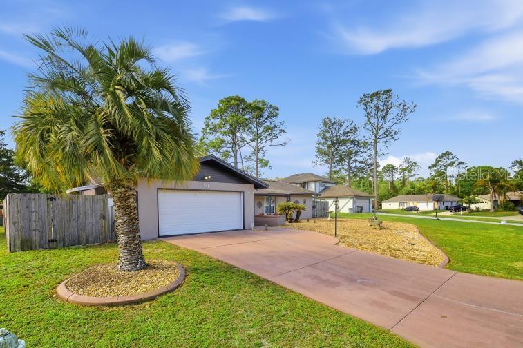 A single-story house with a white garage door, a palm tree, and a concrete driveway — 60 BLAINE DRIVE, PALM COAST, FL