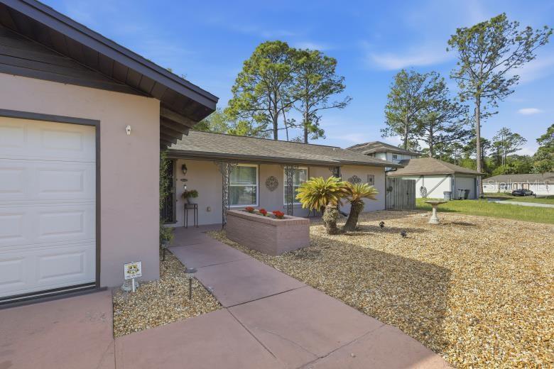 A single-story house with a gravel yard, a brick planter, and a white garage door — 60 BLAINE DRIVE, PALM COAST, FL