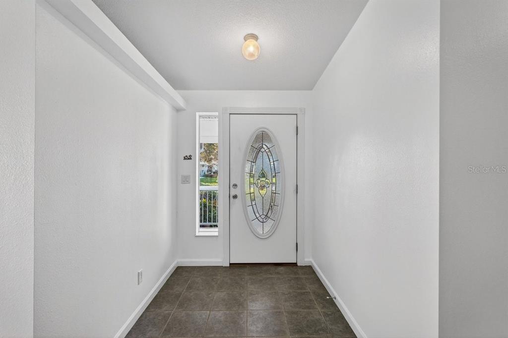 An entryway features white walls, a tiled floor, and a door with an oval glass insert — 332 MARSH LANDING LOOP, OAK HILL, FL
