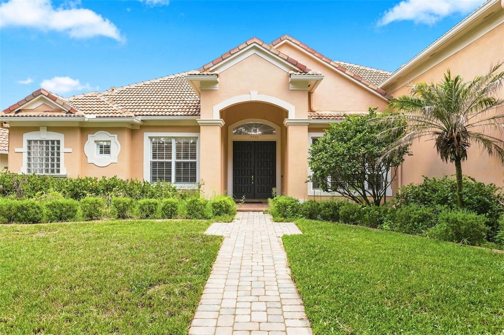 A single-story house with a peach-colored exterior, a tiled roof, and a paved walkway — 7746 DEBEAUBIEN DRIVE, ORLANDO, FL