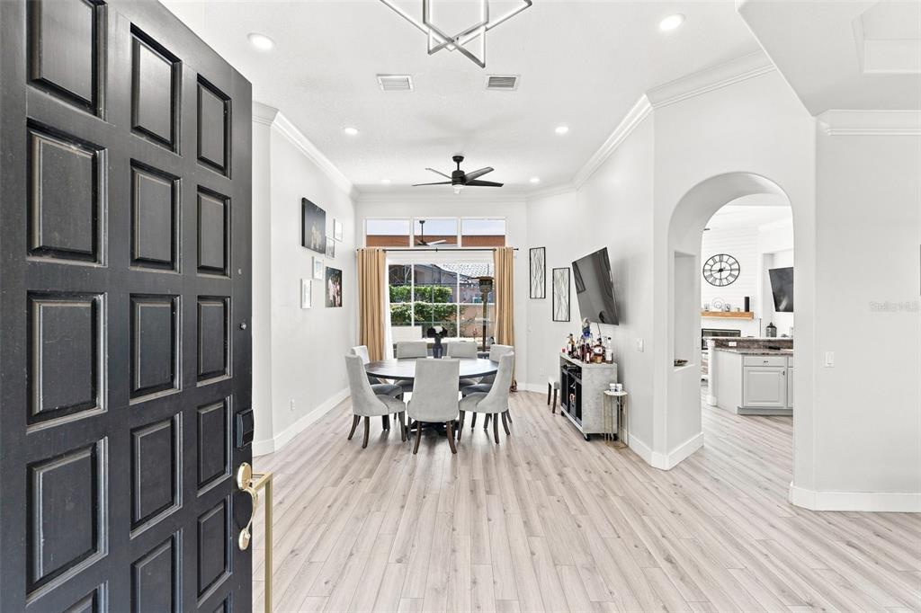 A dining room with light wood floors, a round table, and an arched entryway — 7746 DEBEAUBIEN DRIVE, ORLANDO, FL