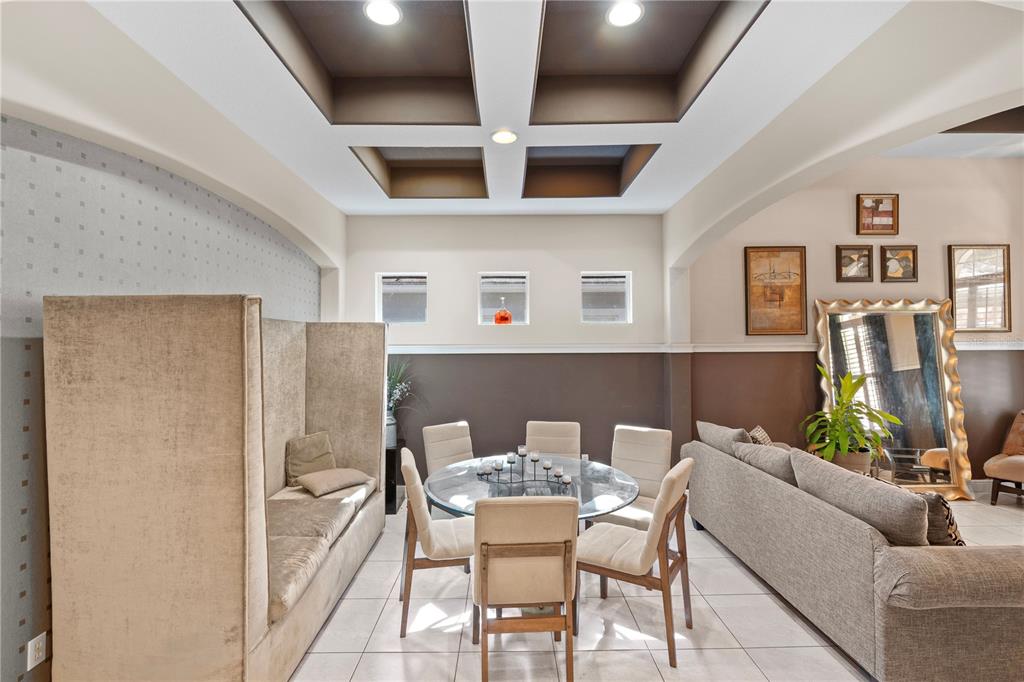 A dining area features a glass table, upholstered chairs, a high-backed bench, and coffered ceilings — 9018 VIA BELLA NOTTE, ORLANDO, FL