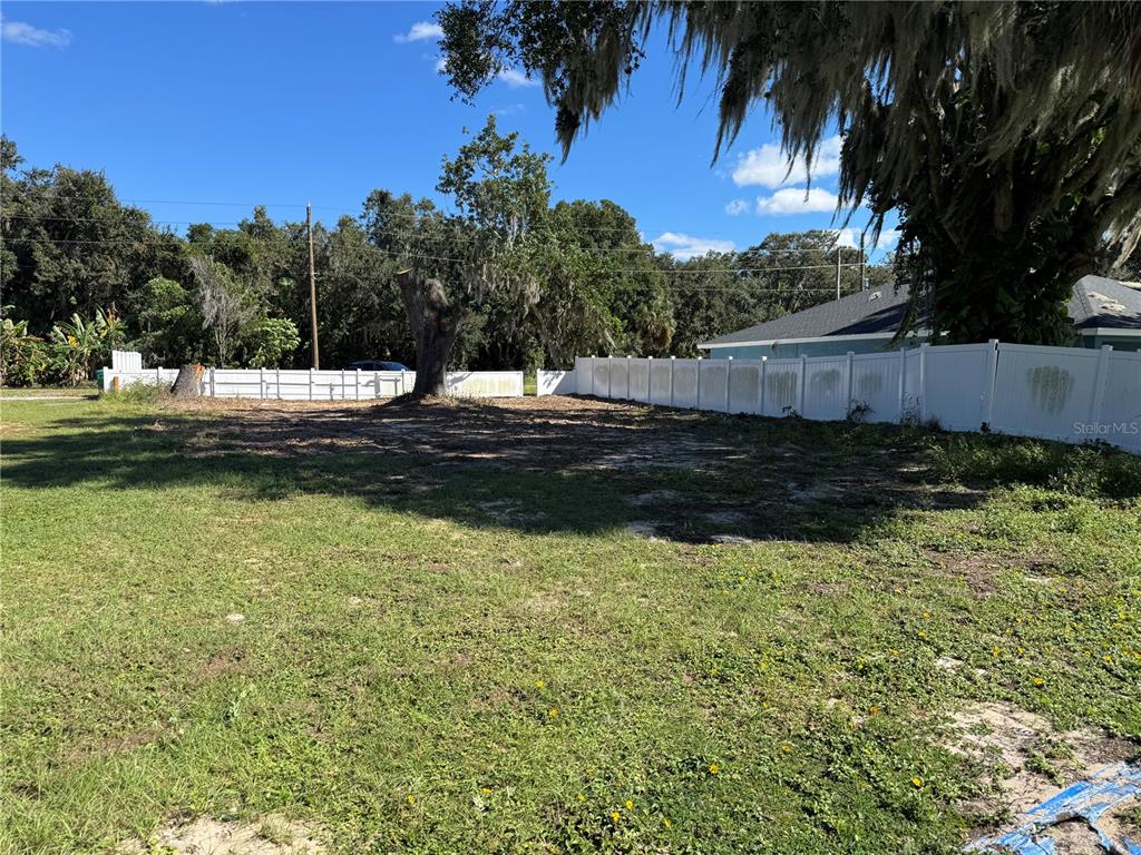 A grassy, cleared residential lot features a white vinyl fence and mature trees — 1200 NORTHSHORE DRIVE, EUSTIS, FL