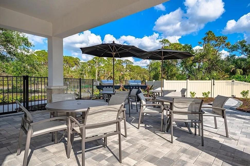 A modern kitchen features gray cabinets, a quartz-topped island, and a sliding glass door — 7154 GRAND FOREST WAY, NOKOMIS, FL