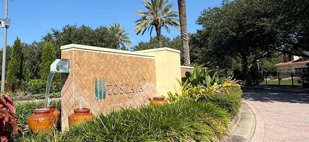 A stone monument sign for Toscana features a water fountain with decorative pots and landscaping — 6977 DOLCE STREET, ORLANDO, FL