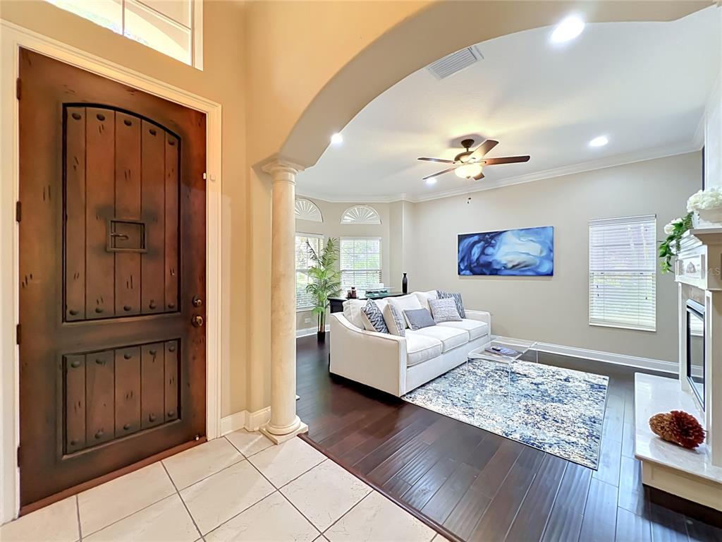 A tiled entryway leads into a living room with dark wood floors and a white sofa — 6977 DOLCE STREET, ORLANDO, FL