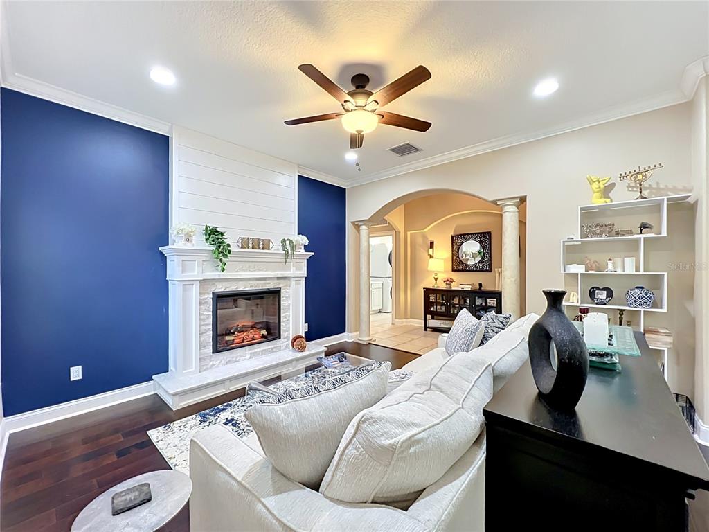 A living room features a fireplace with a white mantel, blue accent walls, and furniture — 6977 DOLCE STREET, ORLANDO, FL