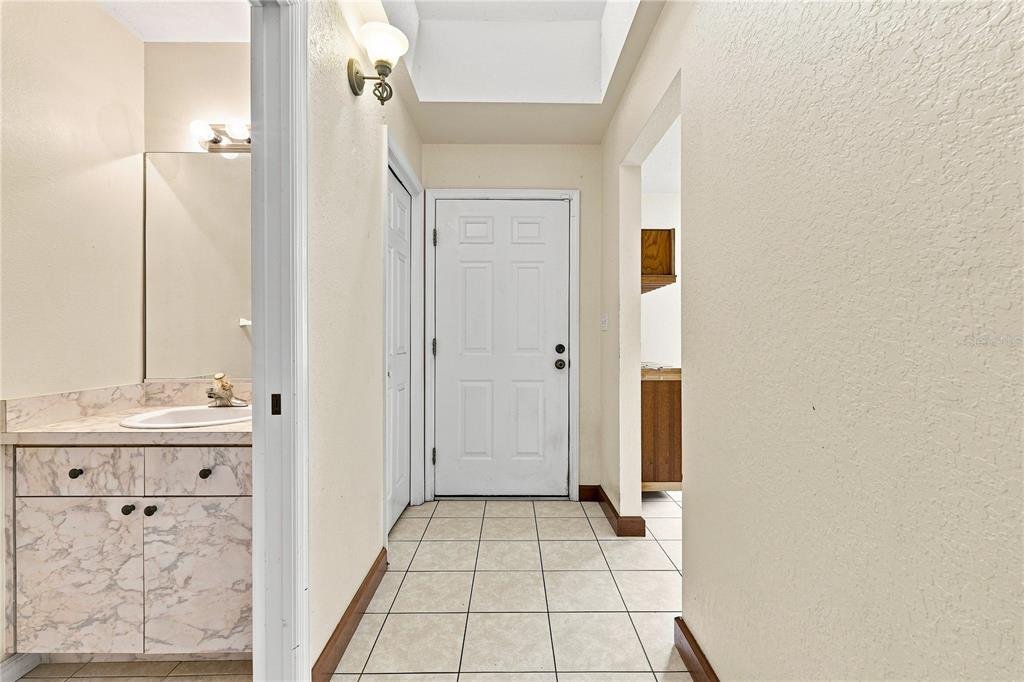 A tiled entryway features a white front door, a marble-topped vanity, and a recessed ceiling — 1220 ALEXANDER WAY, LARGO, FL