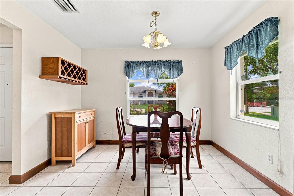 A dining room features a wooden table with four chairs, tile flooring, and two windows — 1220 ALEXANDER WAY, LARGO, FL