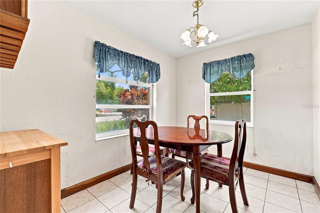A dining area features a round wooden table, four chairs, tiled floors, and two windows — 1220 ALEXANDER WAY, LARGO, FL