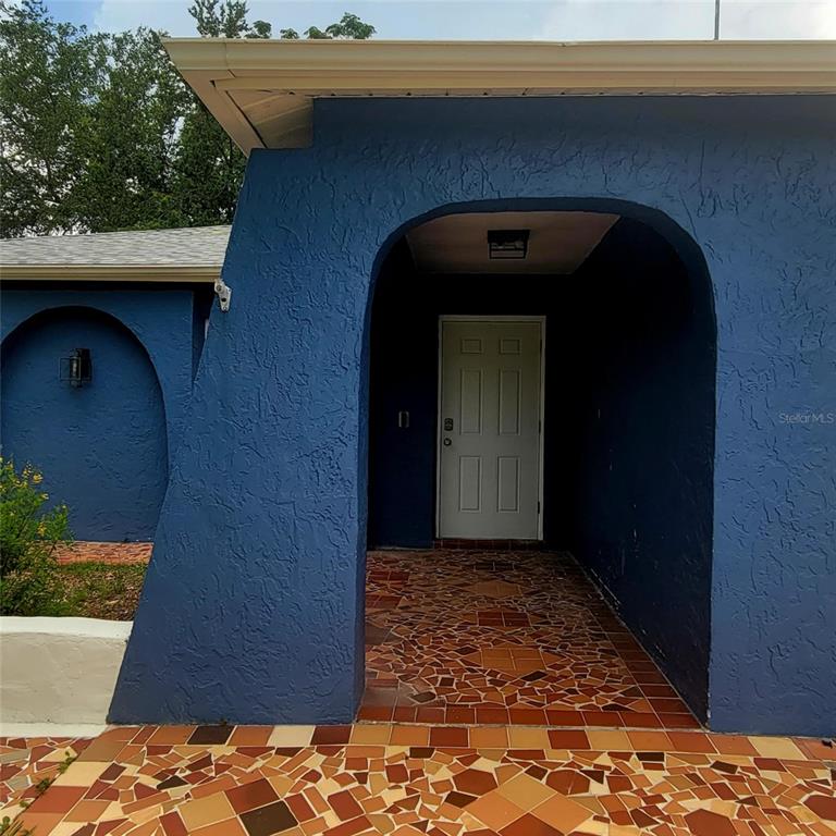 A blue stucco exterior features a covered entryway with a mosaic tile floor — 8504 LAFITTE DRIVE, HUDSON, FL