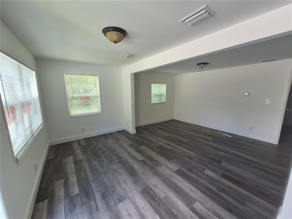 An empty room with white walls, gray wood-look flooring, and two windows with blinds — 12599 NW 38TH AVENUE, REDDICK, FL