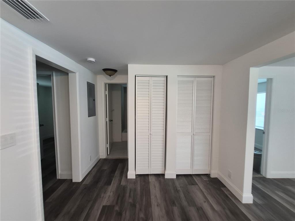 A hallway with grey wood-look flooring, white walls, and two white louvered closet doors — 12599 NW 38TH AVENUE, REDDICK, FL