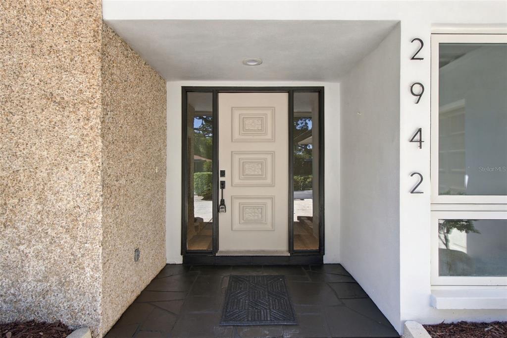 A front entryway features a light-colored door with three square panels and black stone flooring — 2942 CLUBHOUSE DRIVE W, CLEARWATER, FL
