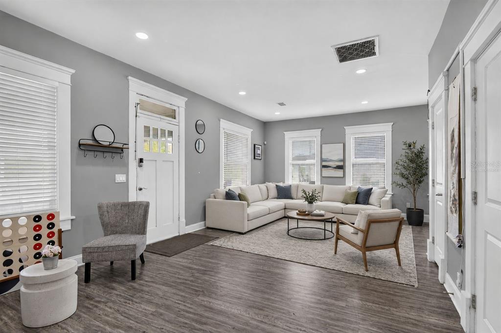 A living room features gray walls, wood-look flooring, a sectional sofa, and a white front door — 4014 N MARGUERITE STREET, TAMPA, FL