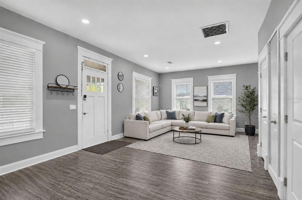 A living room features gray walls, wood-look flooring, a white sectional sofa, and a front door — 4014 N MARGUERITE STREET, TAMPA, FL