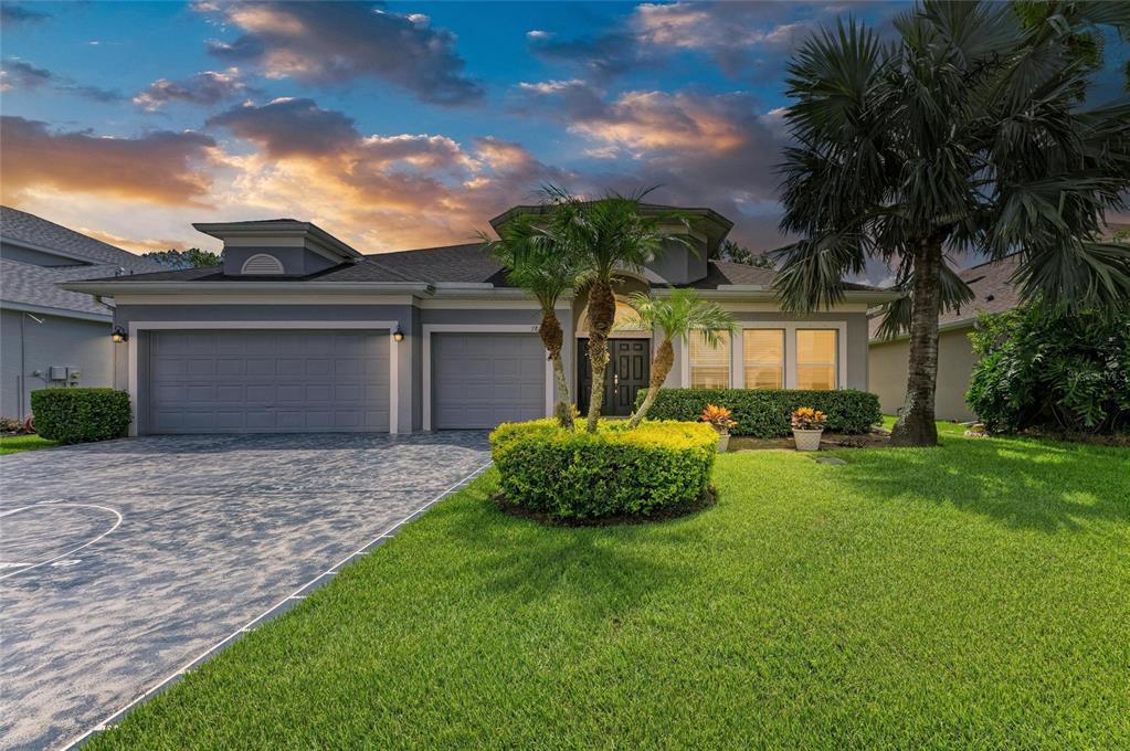A single-story house with a gray exterior, a three-car garage, and a landscaped front yard — 7812 115TH AVENUE E, PARRISH, FL