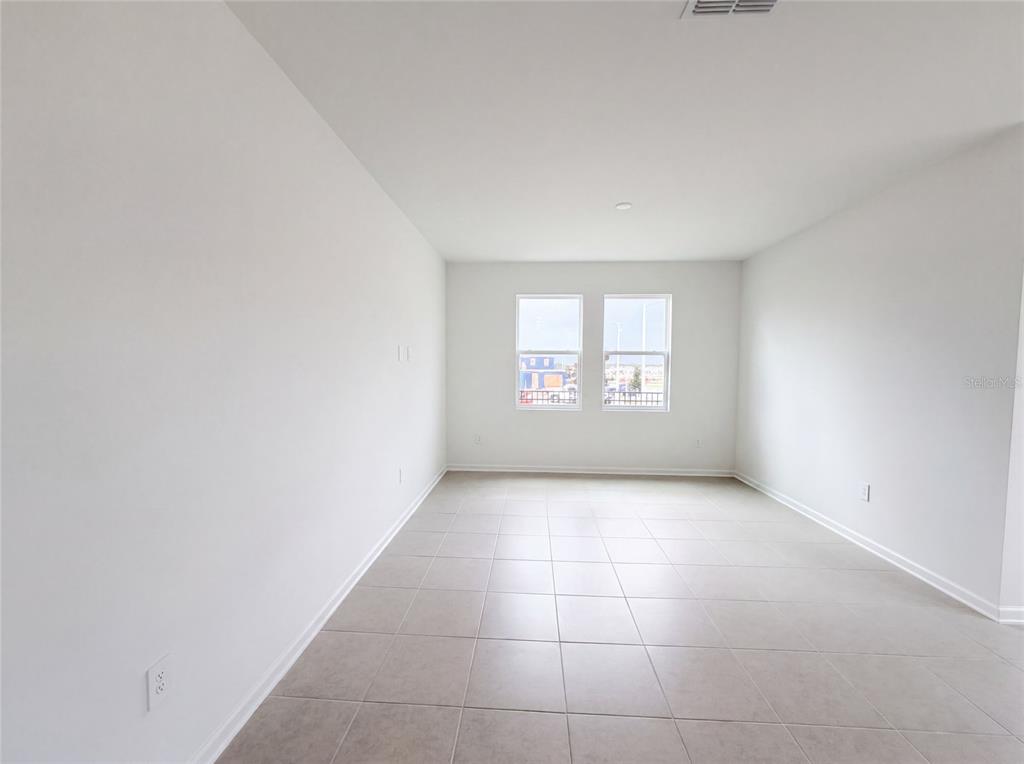 An empty room features white walls, light-colored tile flooring, and two windows on the back wall — 3102 KURTZ TERRACE, DAVENPORT, FL