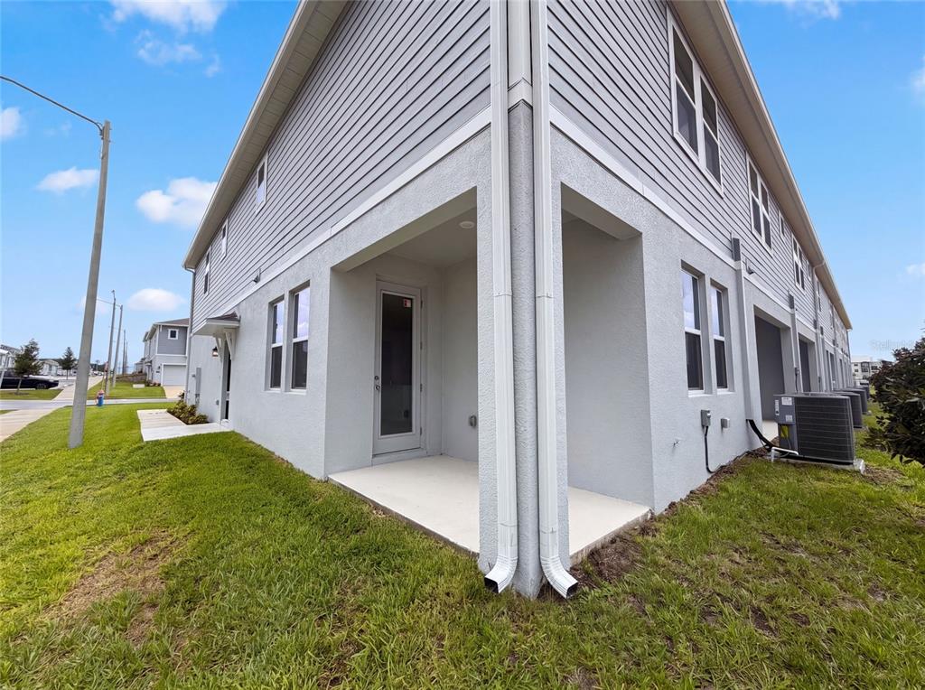 The exterior of a two-story gray townhouse features a covered patio and a side yard — 3102 KURTZ TERRACE, DAVENPORT, FL