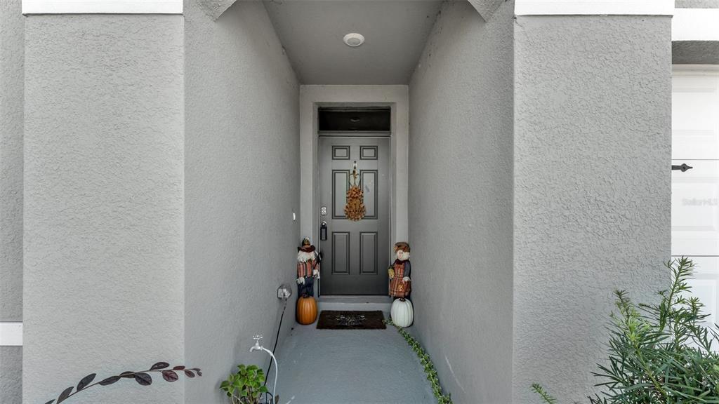 A gray front door with a wreath is flanked by two decorative figures and pumpkins — 3612 DIVING DOVE LANE, BARTOW, FL