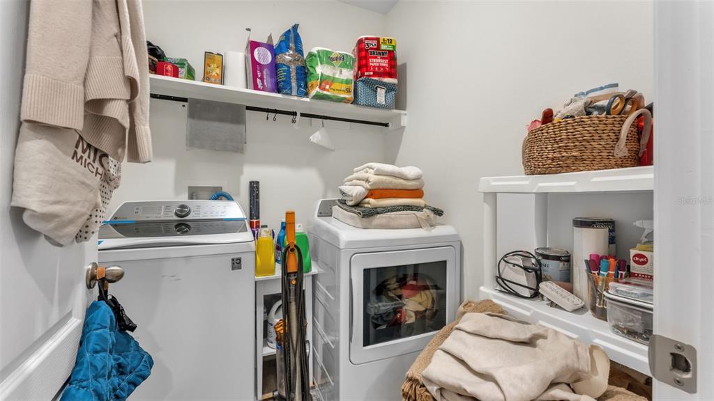 A laundry room with a washer, dryer, white shelving, and various household supplies — 3612 DIVING DOVE LANE, BARTOW, FL