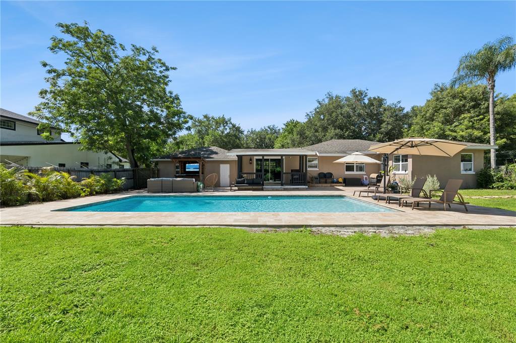 A backyard features a rectangular swimming pool, a covered patio, and a grassy lawn — 2333 WESTMINSTER COURT, WINTER PARK, FL