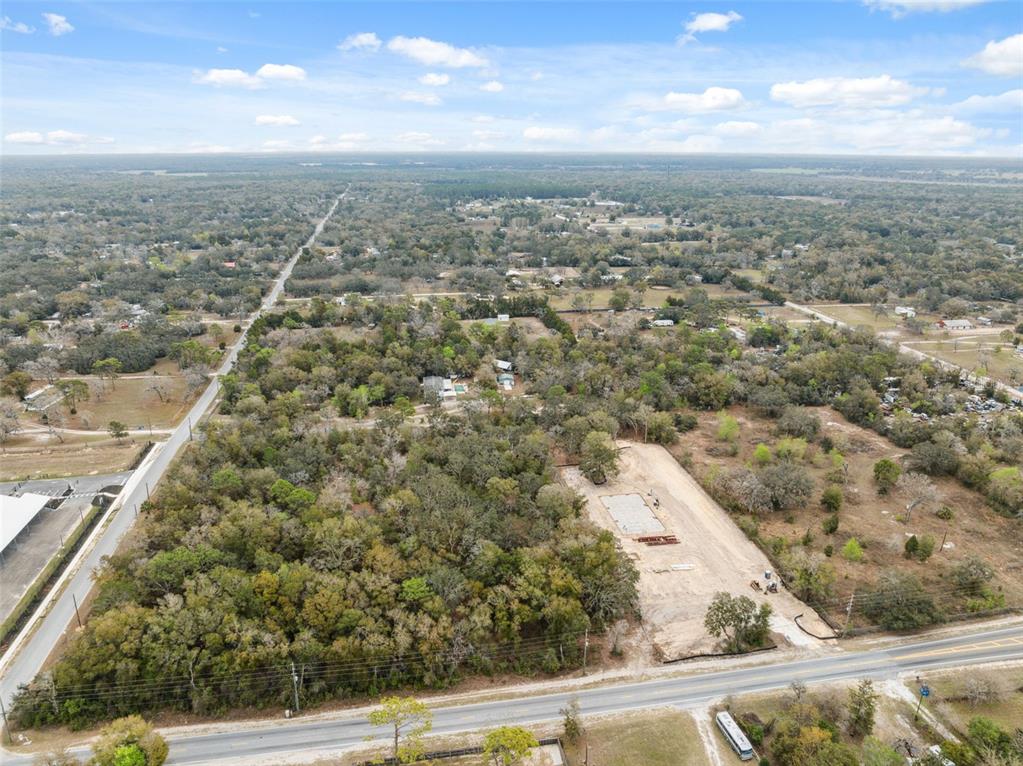 An aerial view shows a wooded lot with a cleared building foundation near a road — 16308 SHADY HILLS ROAD, SPRING HILL, FL