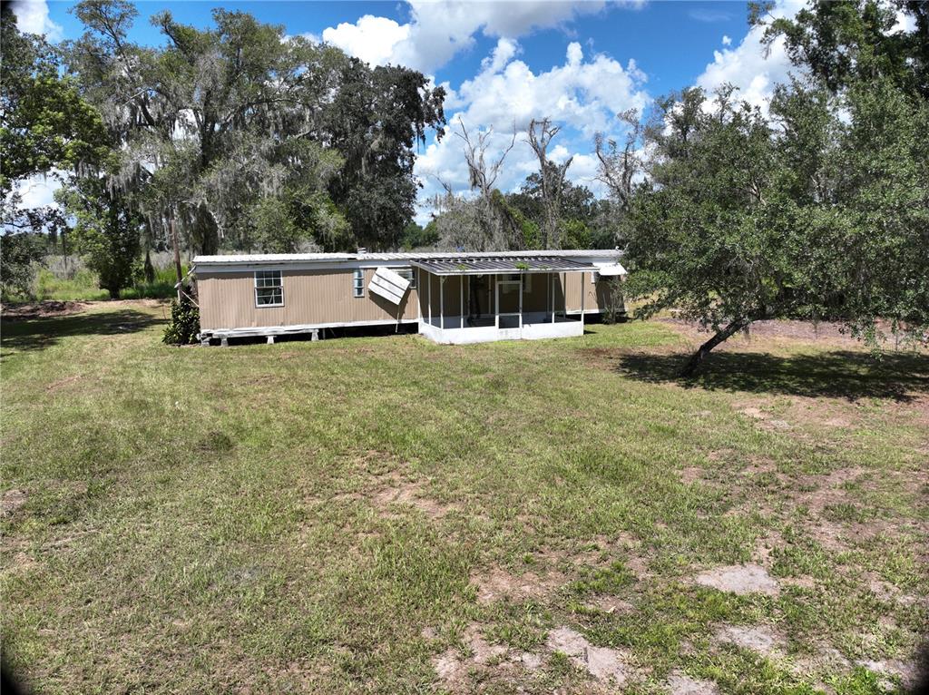 An exterior view of a single-wide mobile home with a screened-in porch and metal roof — 3423 SW KABRICH TERRACE, ARCADIA, FL