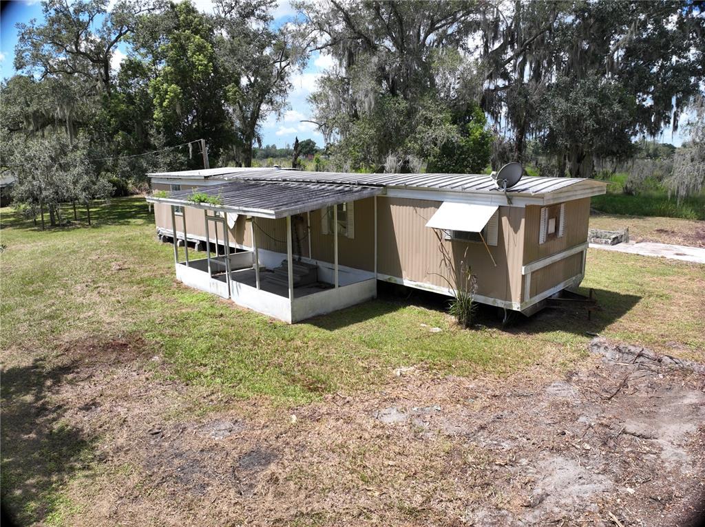 An exterior view of a tan mobile home with a metal roof and screened porch — 3423 SW KABRICH TERRACE, ARCADIA, FL