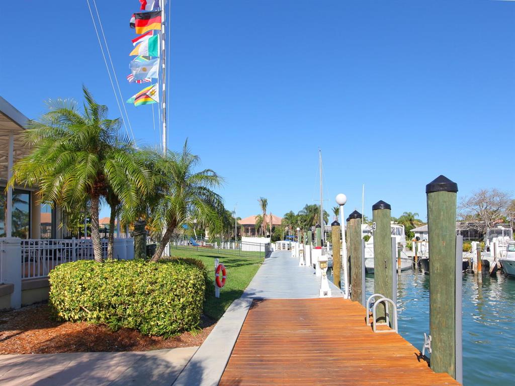 A wooden dock leads toward a marina with boats under a clear blue sky — 332 BOB WHITE WAY, SARASOTA, FL