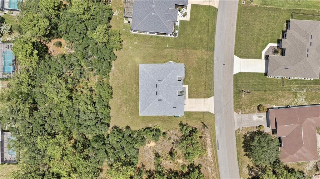 An aerial view shows a house with a gray roof surrounded by grass and trees — 84 VINCA STREET, HOMOSASSA, FL