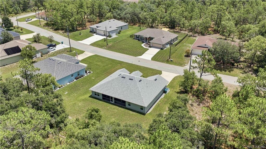 An aerial view shows several suburban houses surrounded by trees and a paved road — 84 VINCA STREET, HOMOSASSA, FL