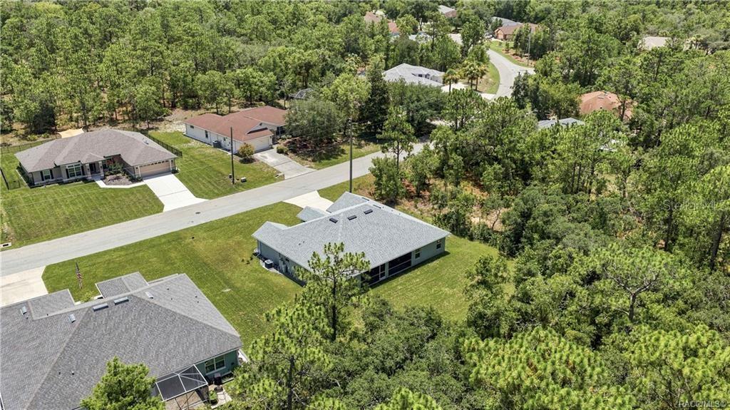 An aerial view shows several suburban houses surrounded by dense trees and paved roads — 84 VINCA STREET, HOMOSASSA, FL
