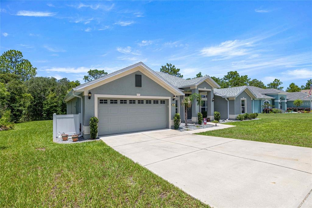 A single-story house with a gray exterior, a two-car garage, and a concrete driveway — 84 VINCA STREET, HOMOSASSA, FL