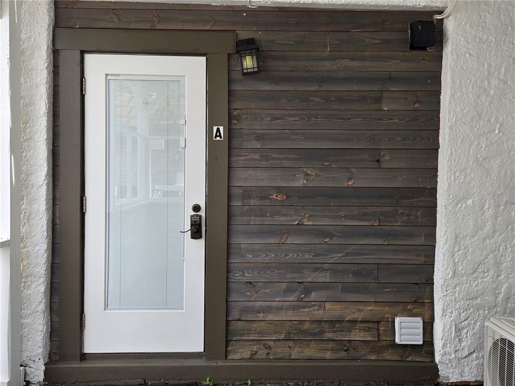 A white door with a glass insert and a dark wood-paneled wall on a porch — 1690 S 10TH STREET UNIT A, HAINES CITY, FL