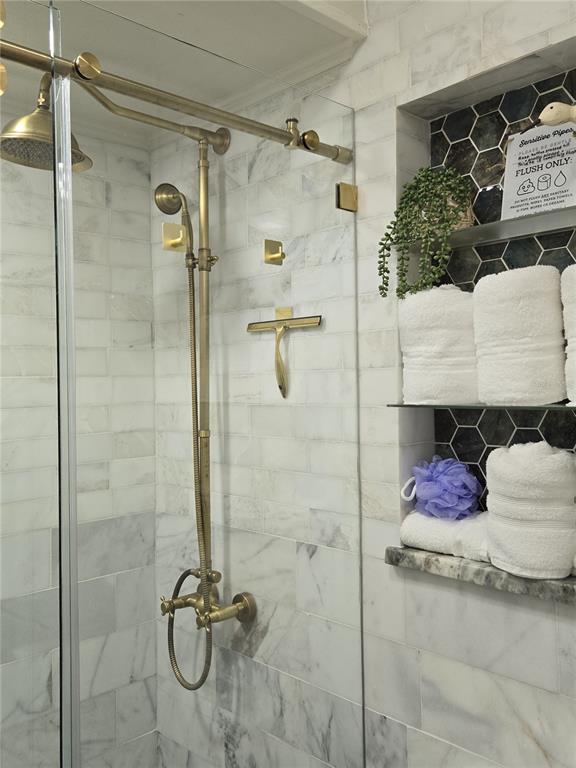 A shower with marble tile walls, brass fixtures, and a recessed shelf with stacked towels — 1690 S 10TH STREET UNIT A, HAINES CITY, FL