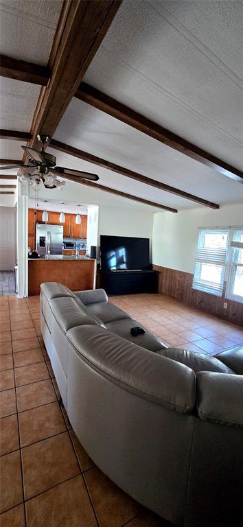 A living room with tile floors, wood ceiling beams, and a view into the kitchen — 14820 COUNTY ROAD 48, ASTATULA, FL