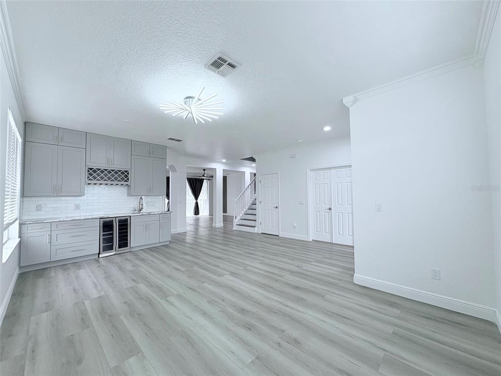 A room with light gray flooring, white walls, and a wet bar with gray cabinetry — 2157 WINTERMERE POINTE DRIVE, WINTER GARDEN, FL
