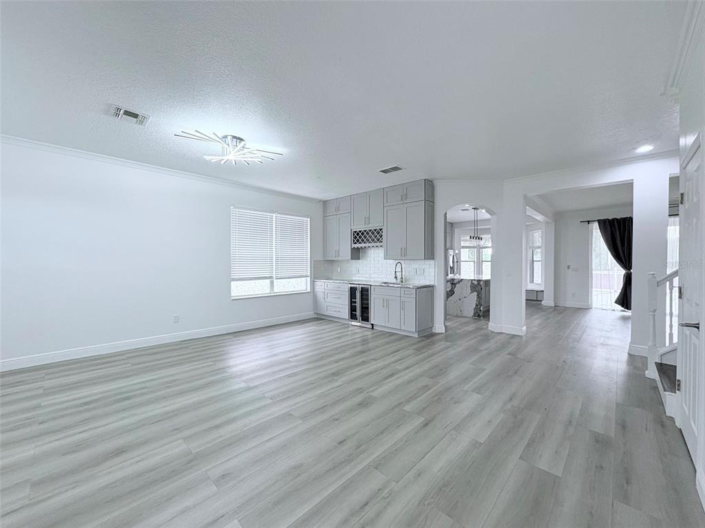 A bright room features light gray wood-look flooring, white walls, and a gray wet bar — 2157 WINTERMERE POINTE DRIVE, WINTER GARDEN, FL